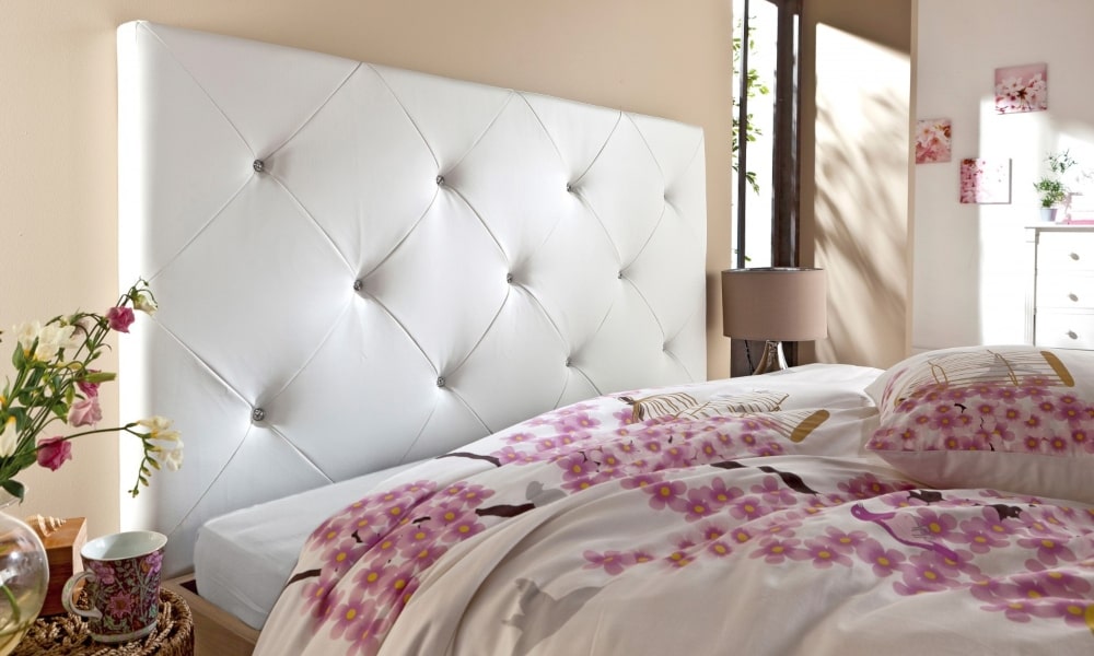 cama con cabecero blanco y edredón de flores